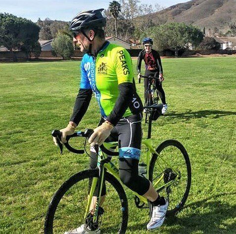 A man is riding a bike in a grassy field with the word peaks on his shirt