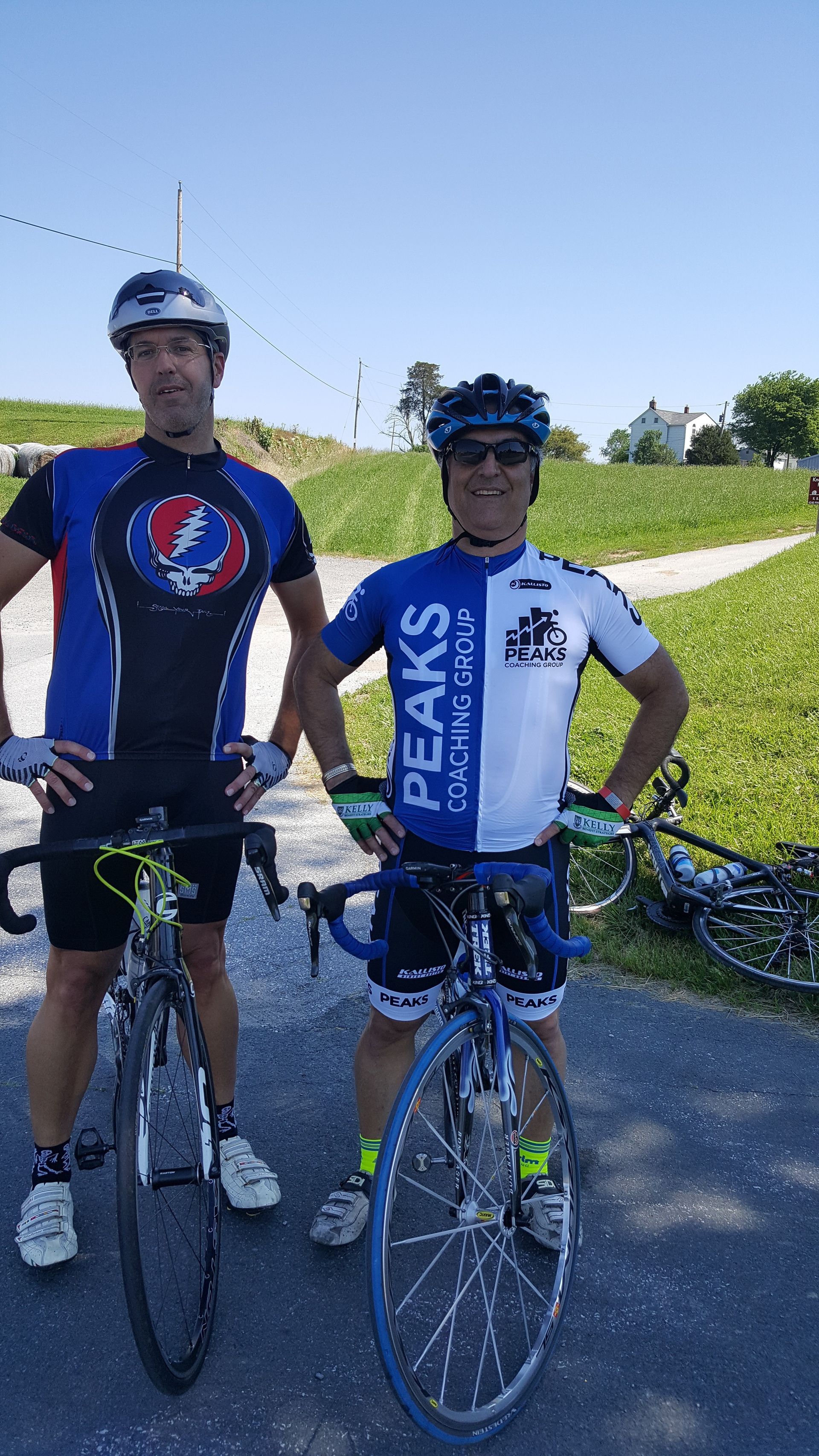 Two men are standing next to each other with bicycles.