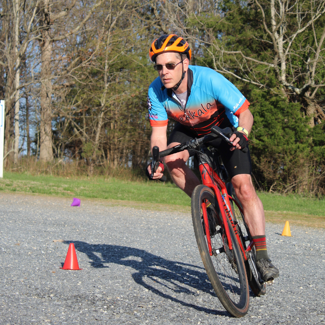 A man wearing a helmet is riding a bike on a gravel road