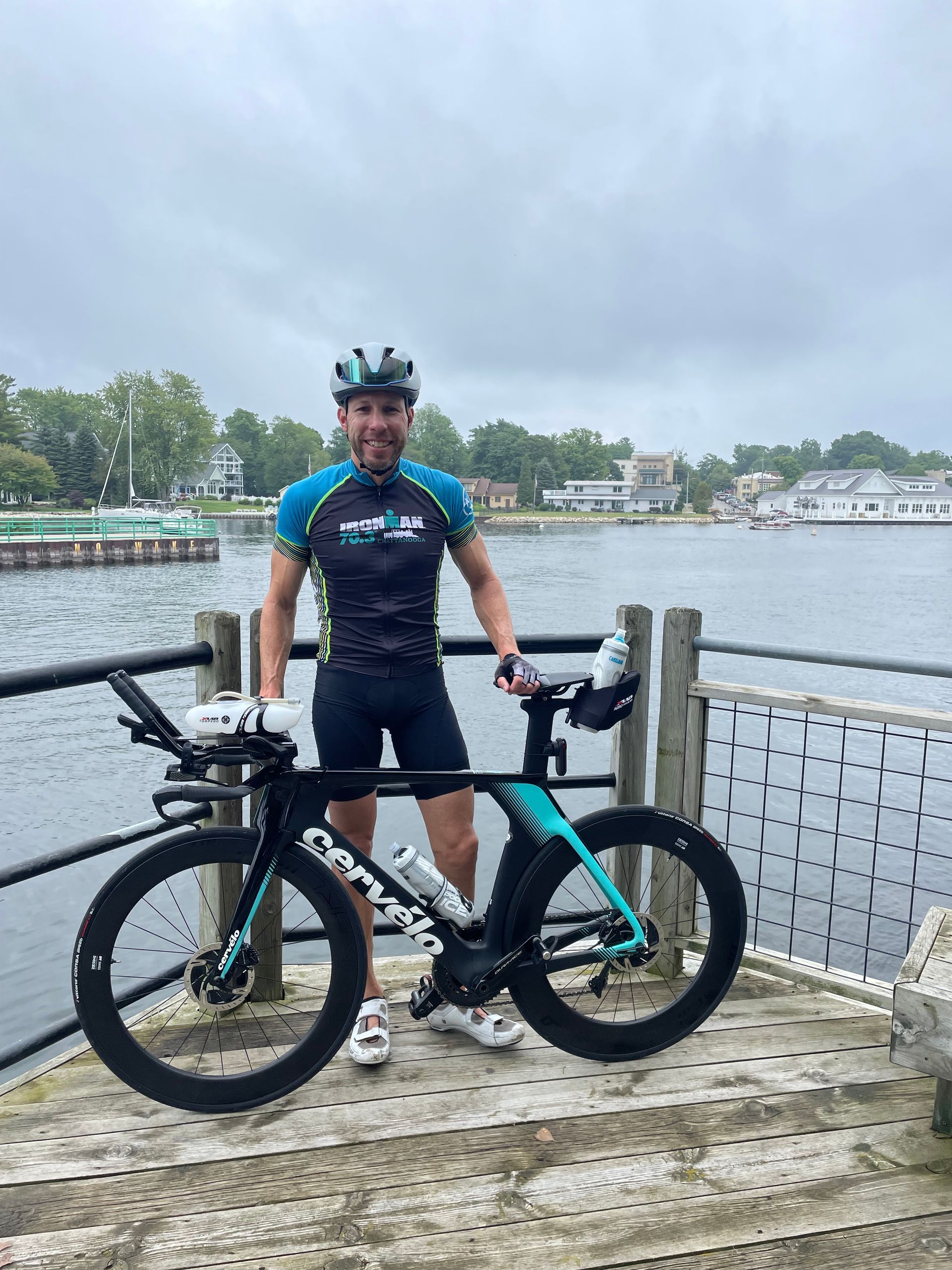 A man is standing next to a bicycle on a dock.