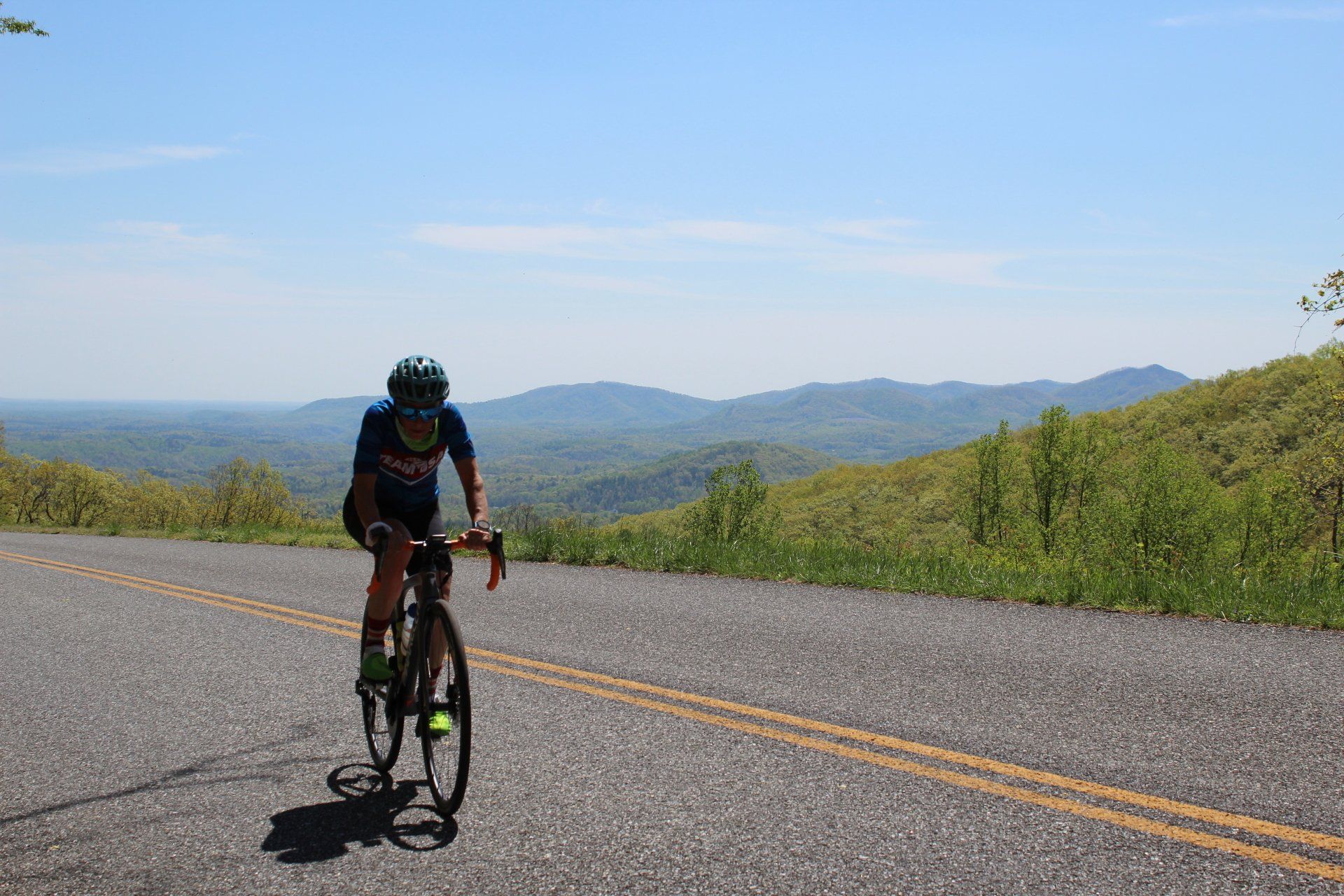 A person is riding a bike down a road with mountains in the background.