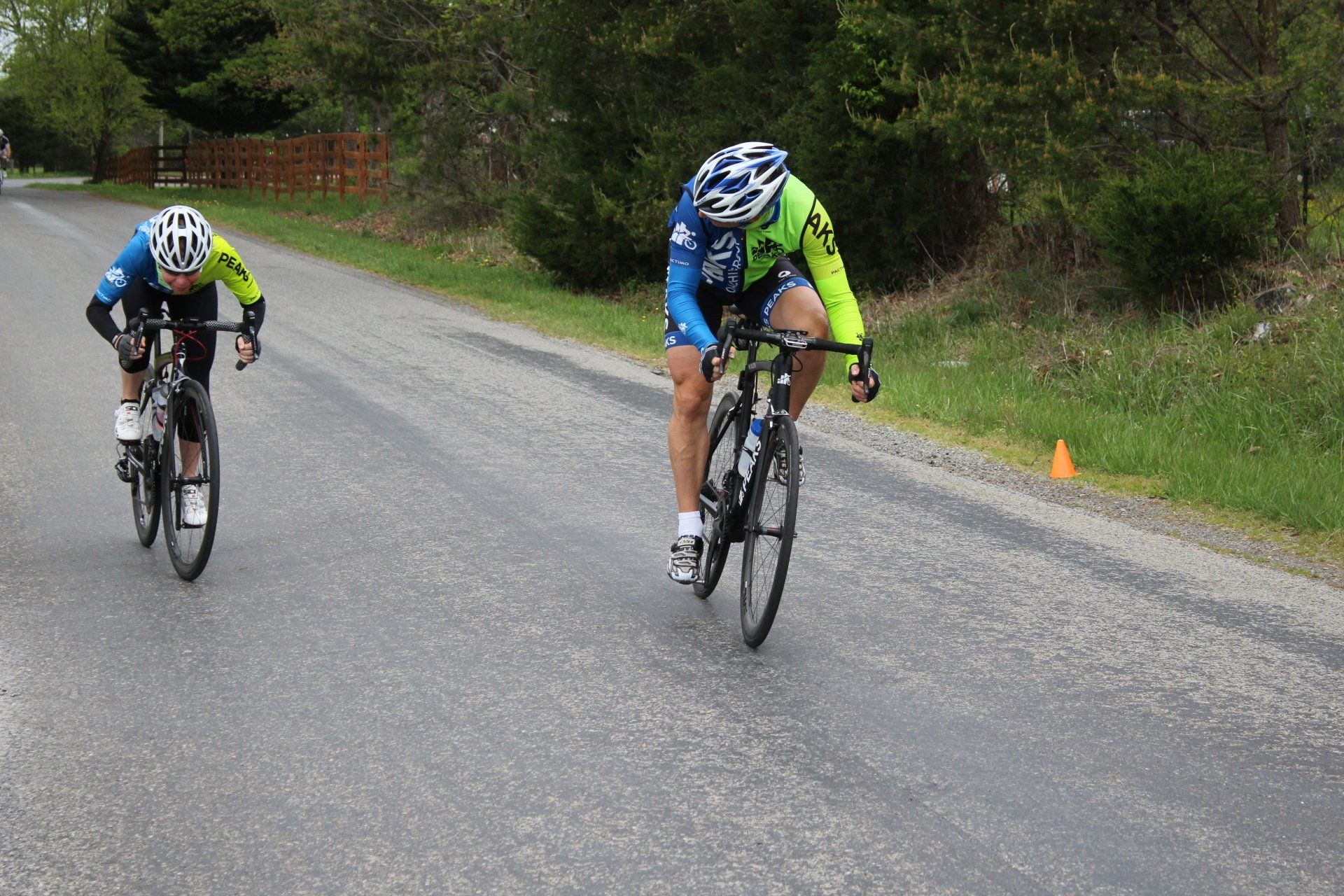 Two people are riding bicycles down a road.