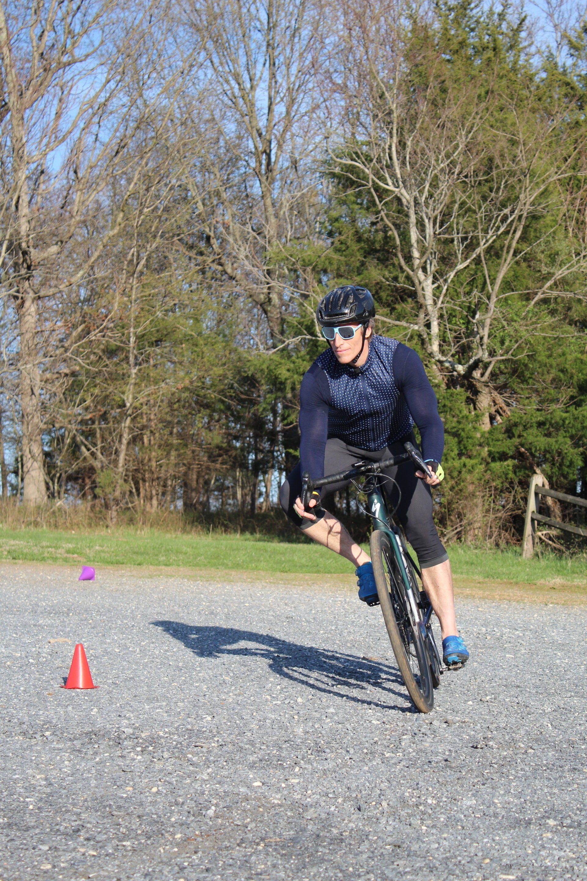 A man is riding a bike on a gravel road.