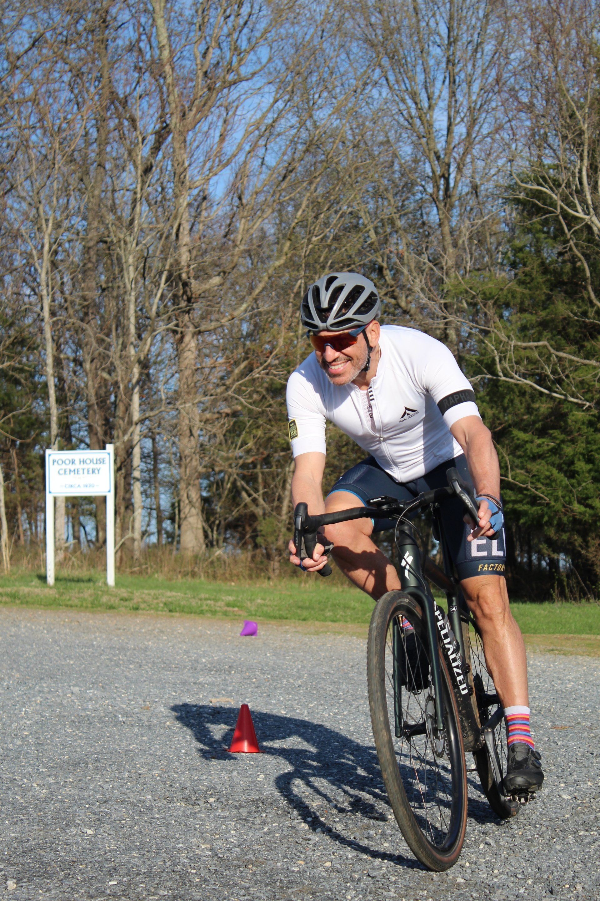 A man is riding a bike on a gravel road.