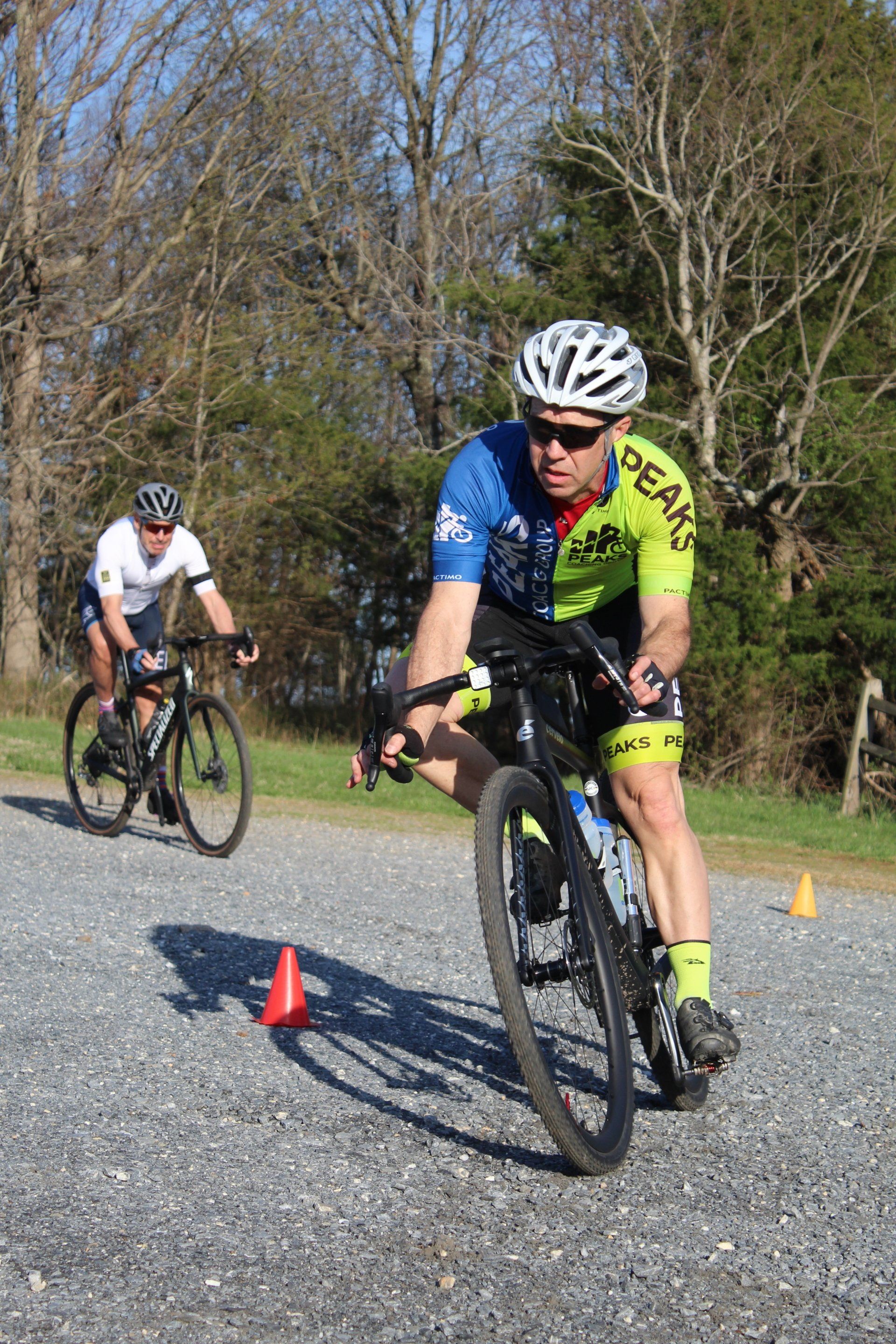 Two men are riding bicycles down a gravel road.