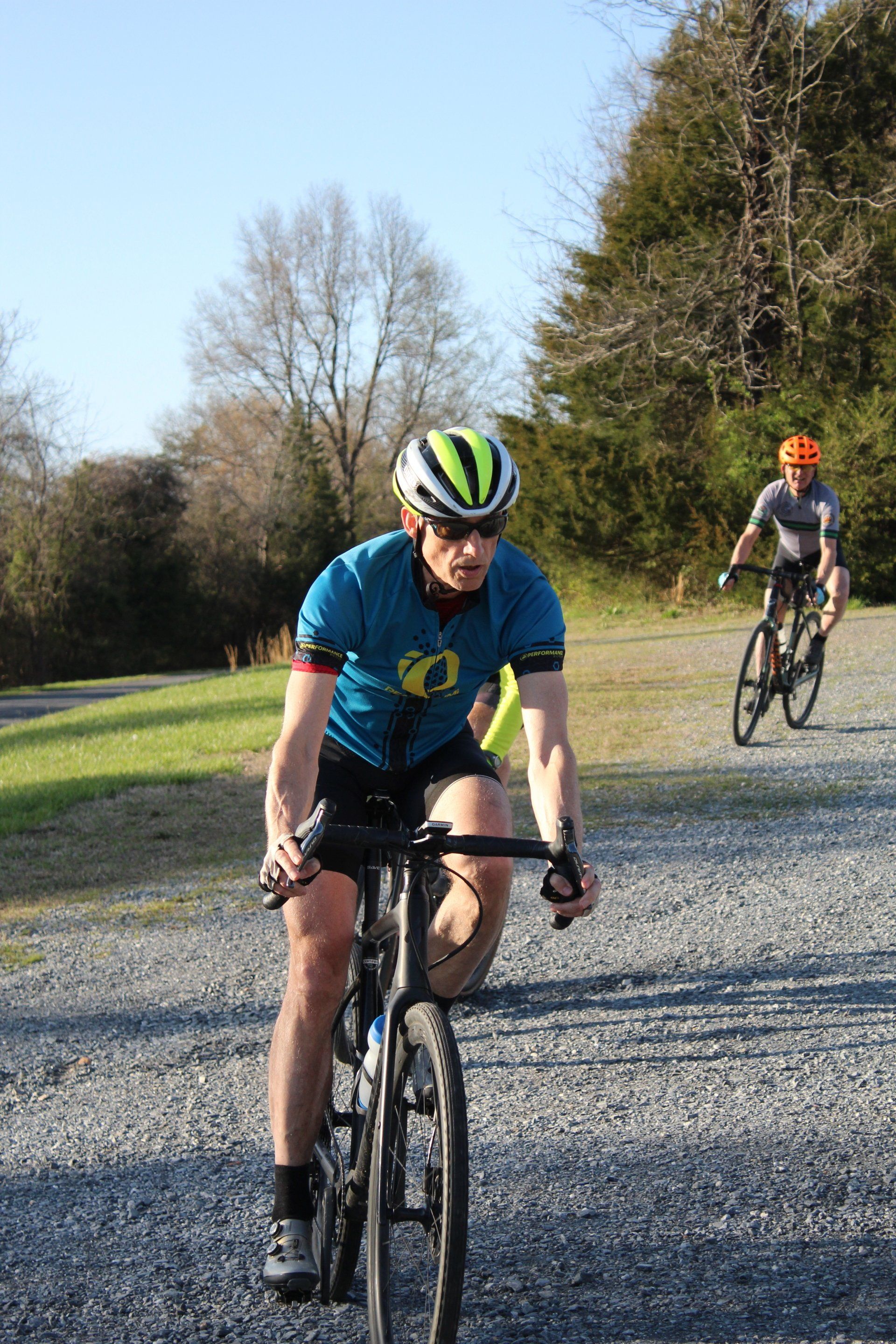 A man is riding a bike on a gravel road.