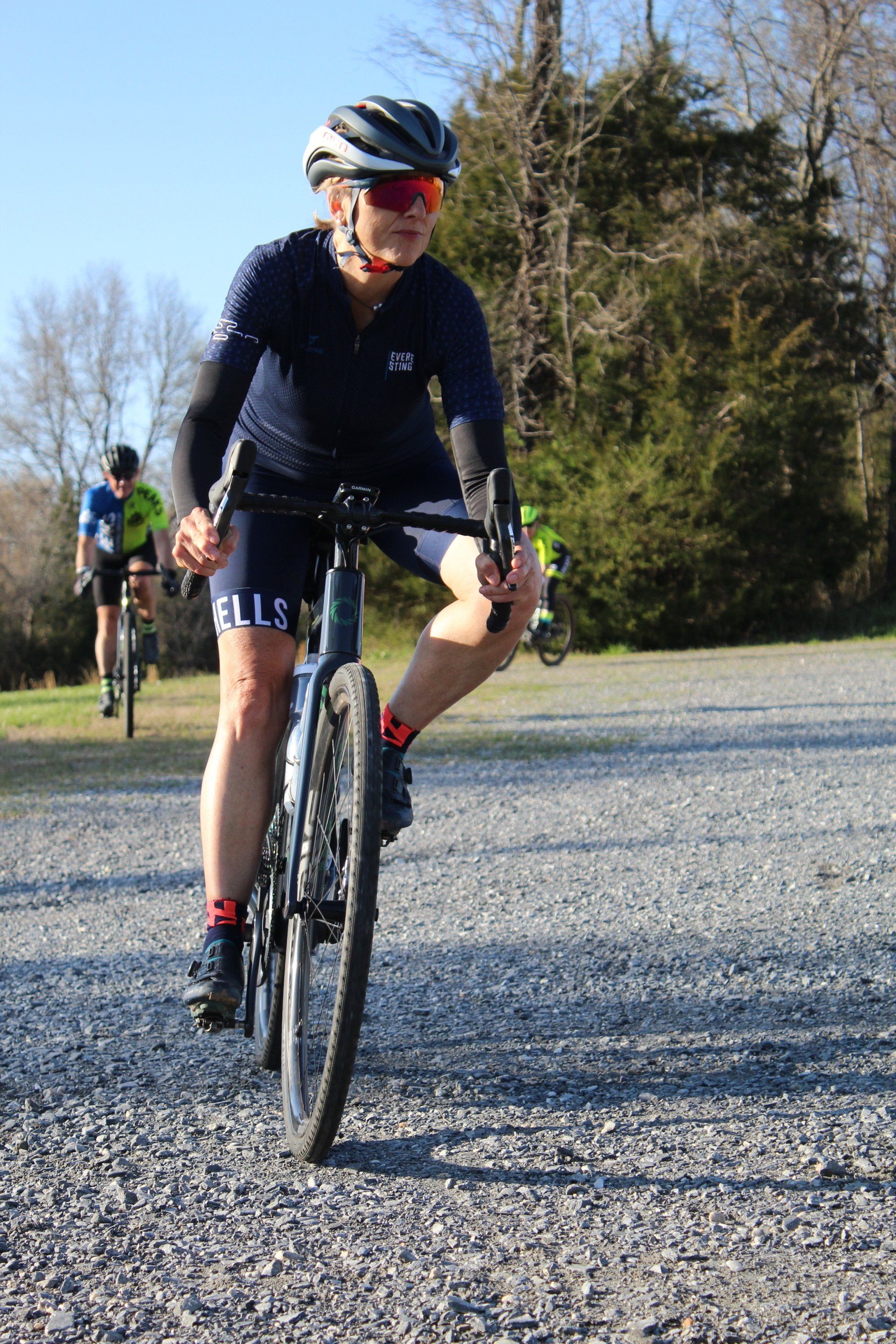 A woman is riding a bike on a gravel road.