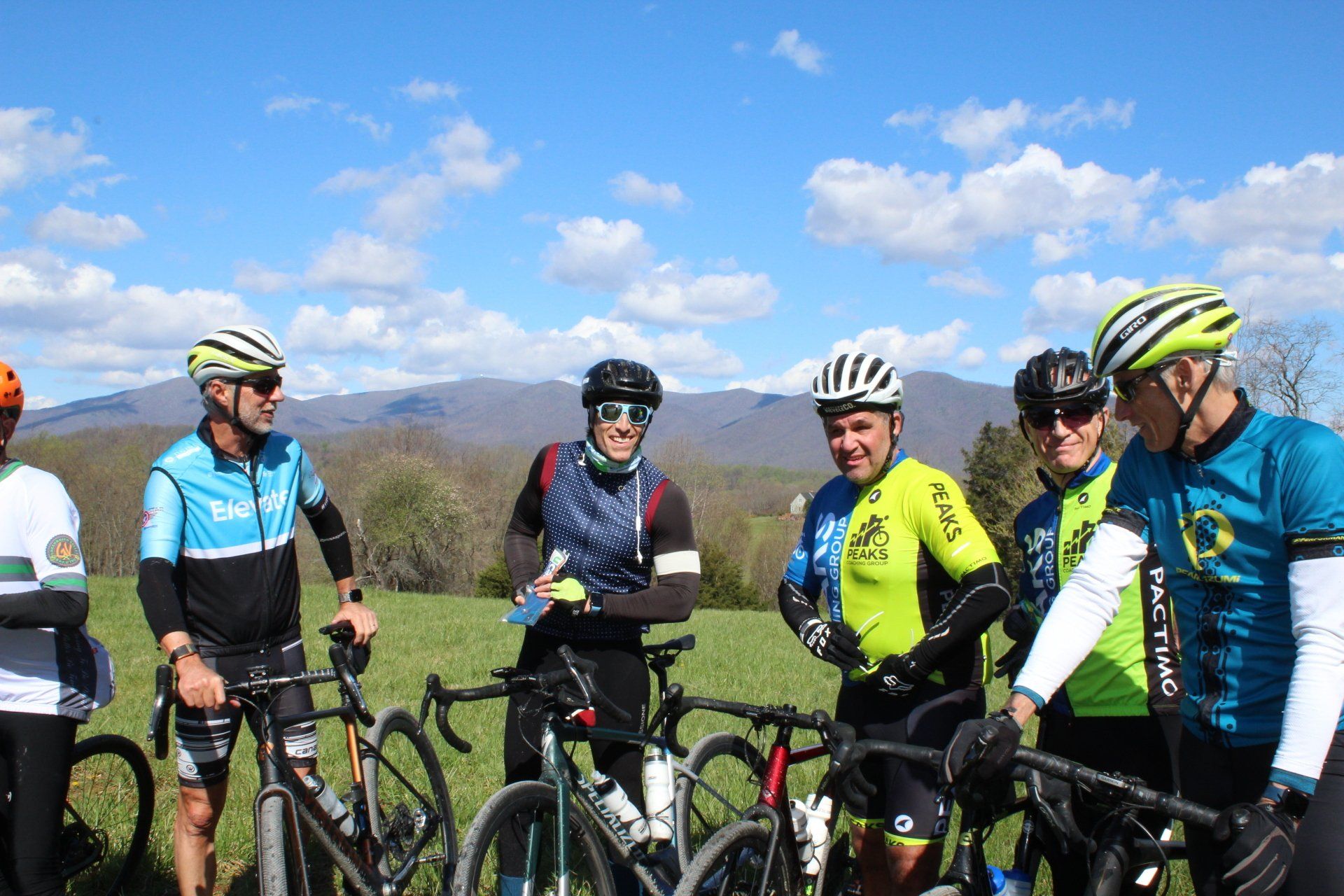 A group of cyclists are standing next to their bikes in a field.