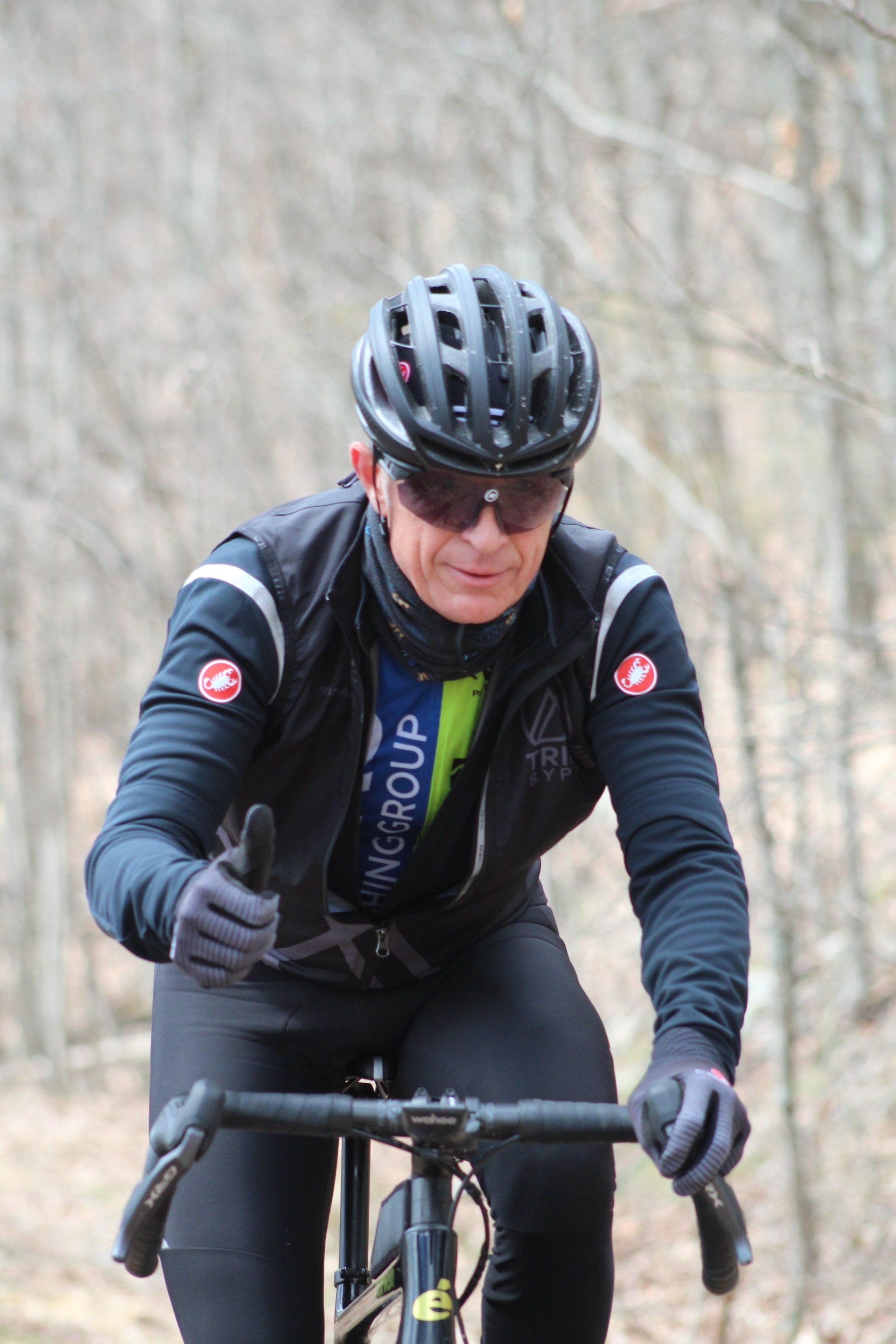 A man wearing a helmet and sunglasses is riding a bike in the woods.