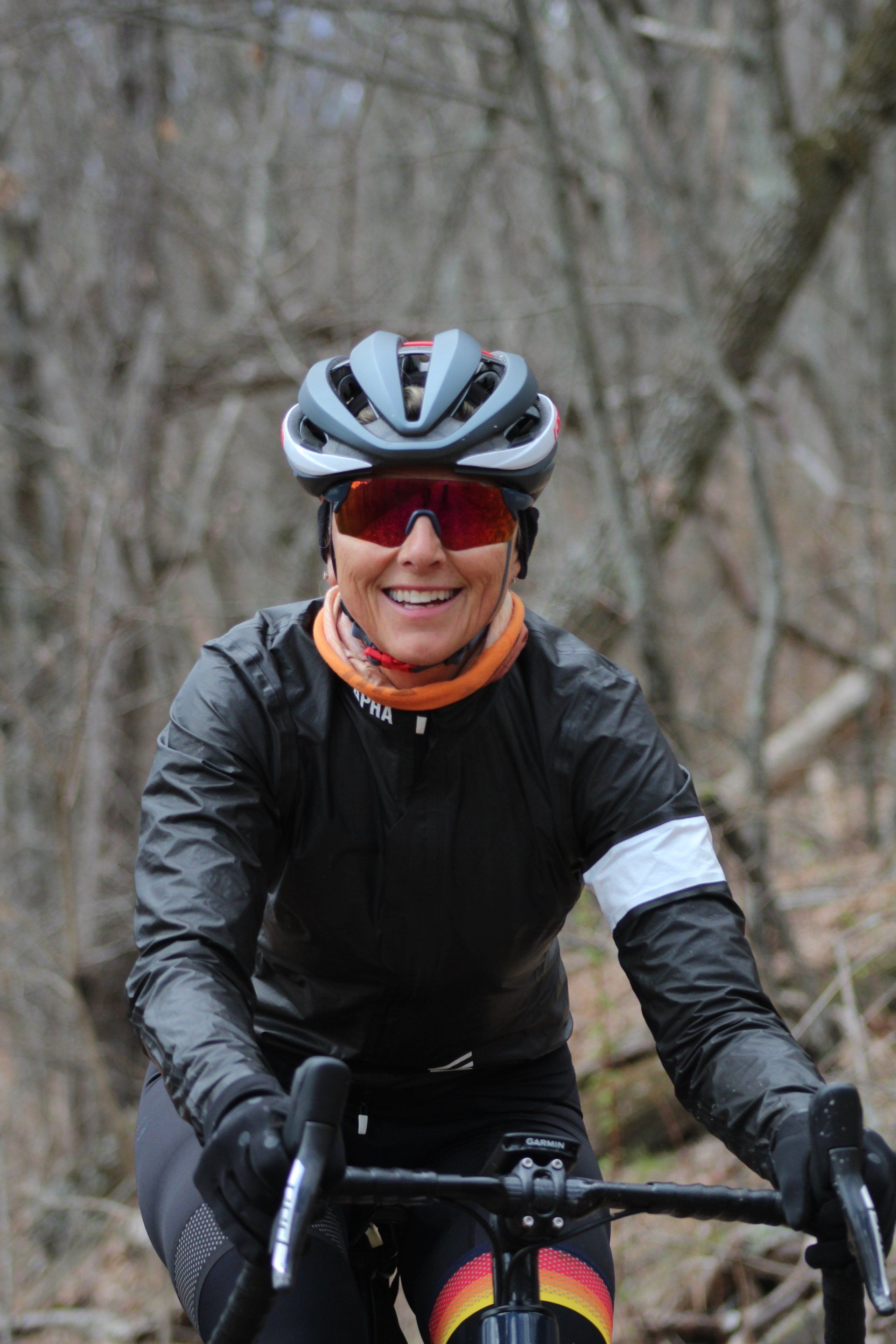 A woman wearing a helmet and sunglasses is riding a bike in the woods.