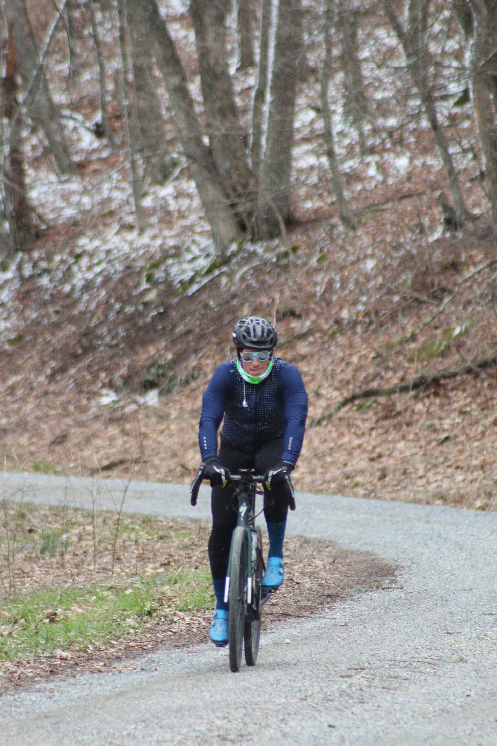 A man is riding a bike down a dirt road in the woods.