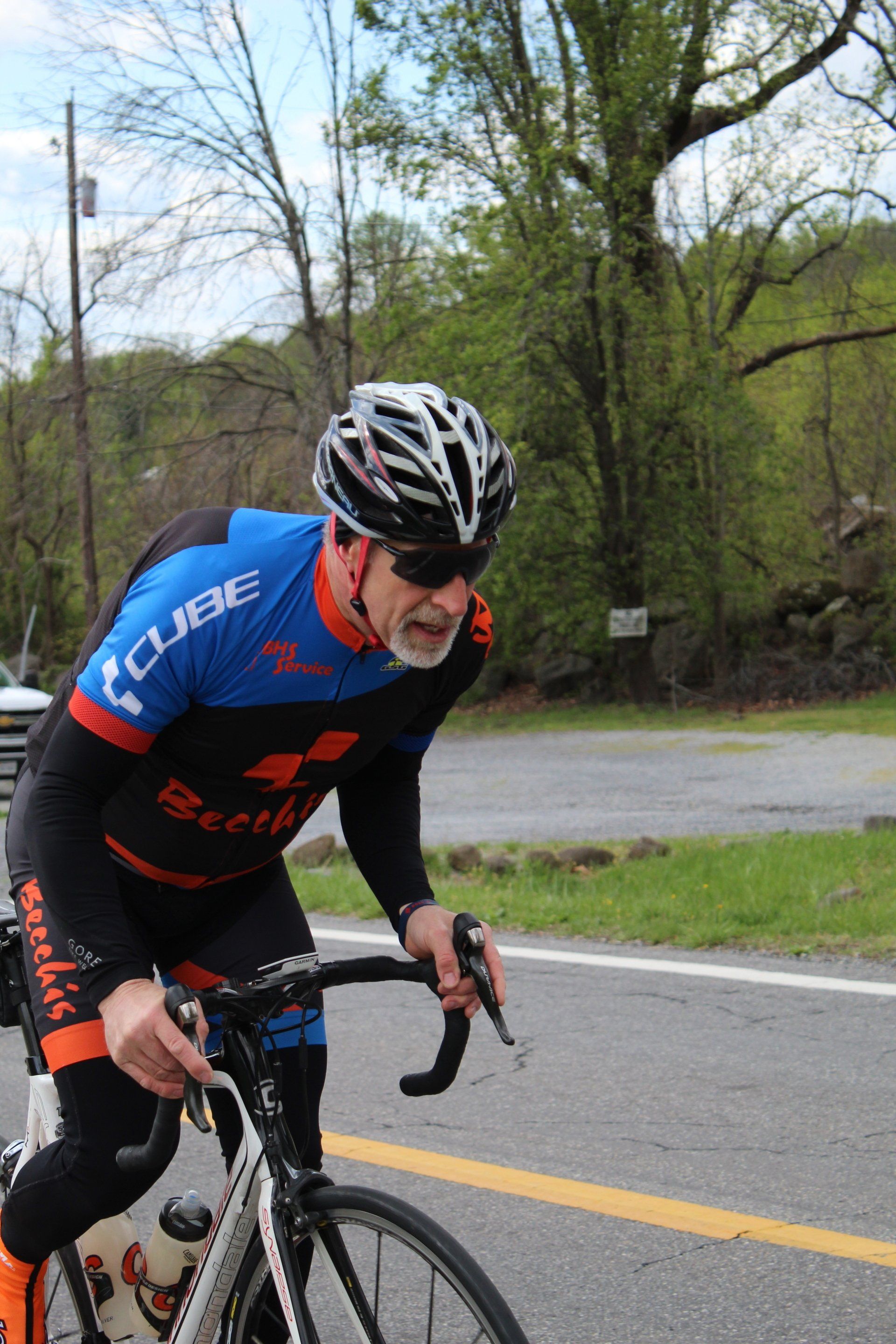 A man wearing a helmet and sunglasses is riding a bike down a road.
