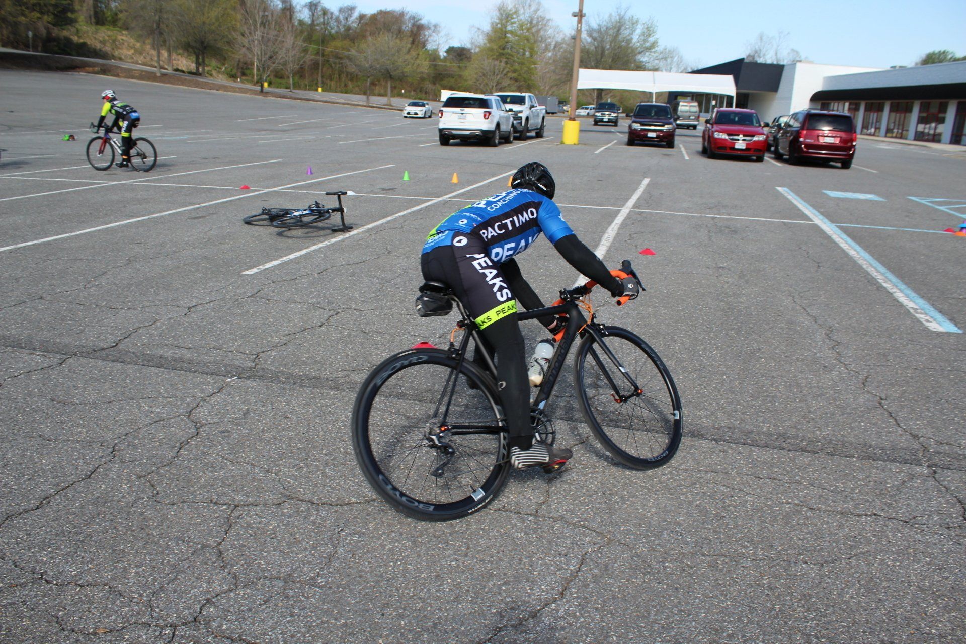 A man is riding a bike in a parking lot.