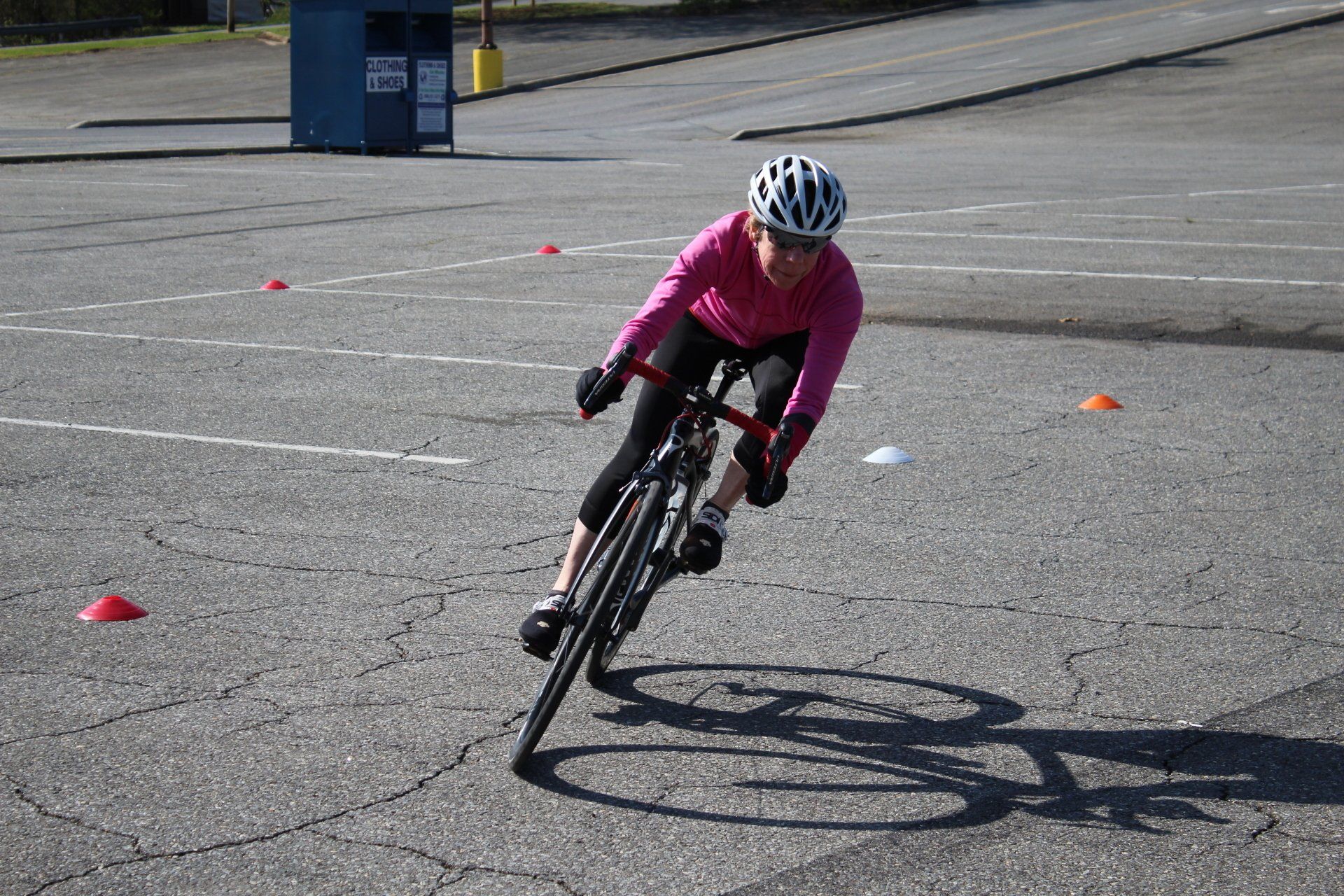 A person wearing a helmet is riding a bike in a parking lot.