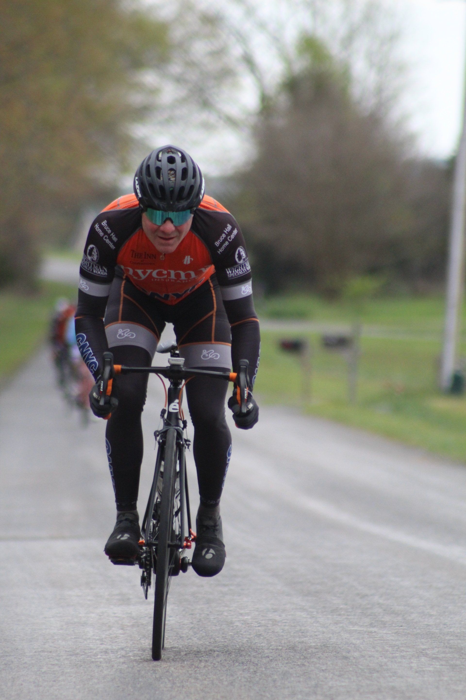 A man wearing a helmet and sunglasses is riding a bike down a road.