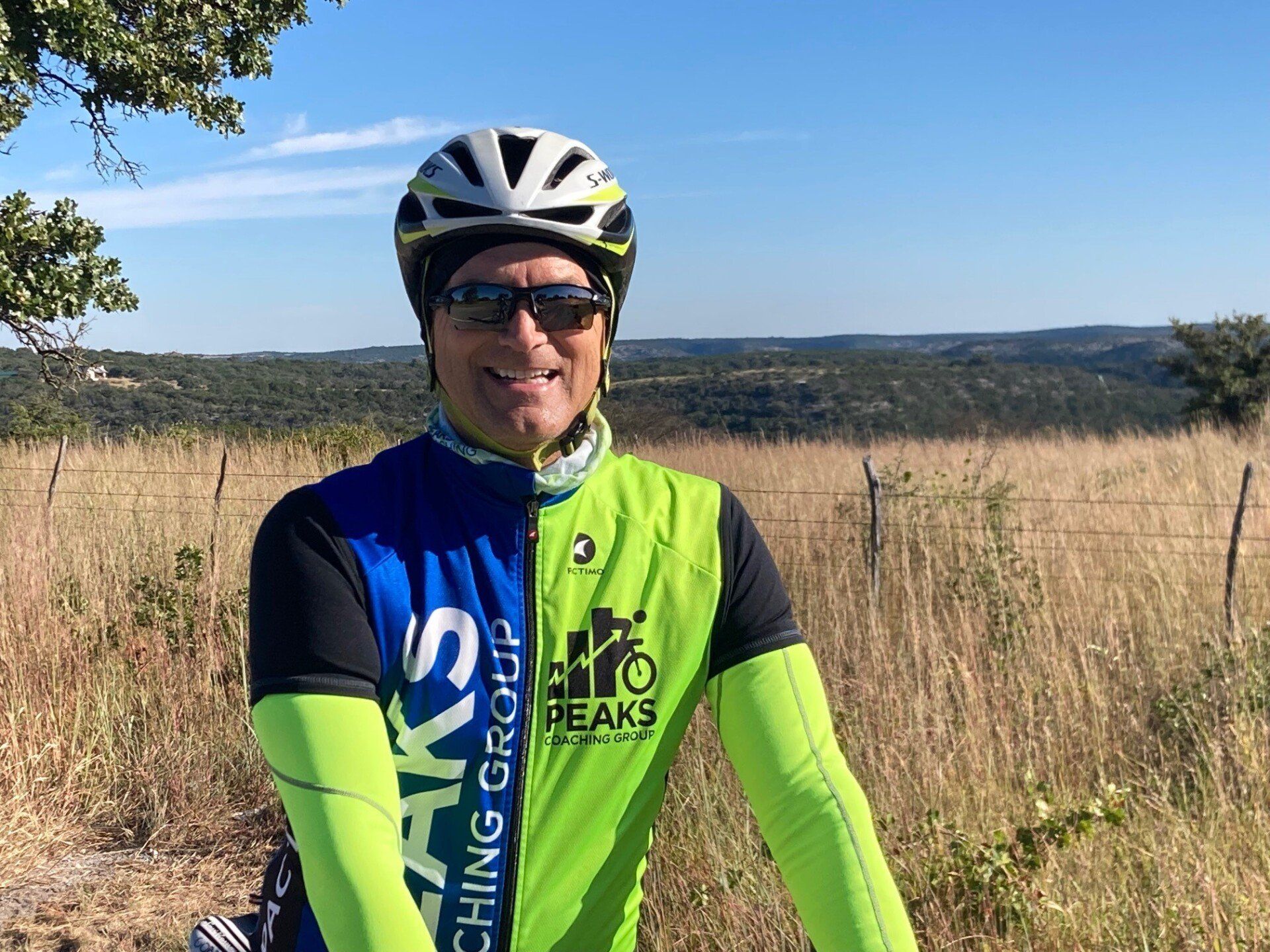 A man wearing a helmet and sunglasses is standing in a field.