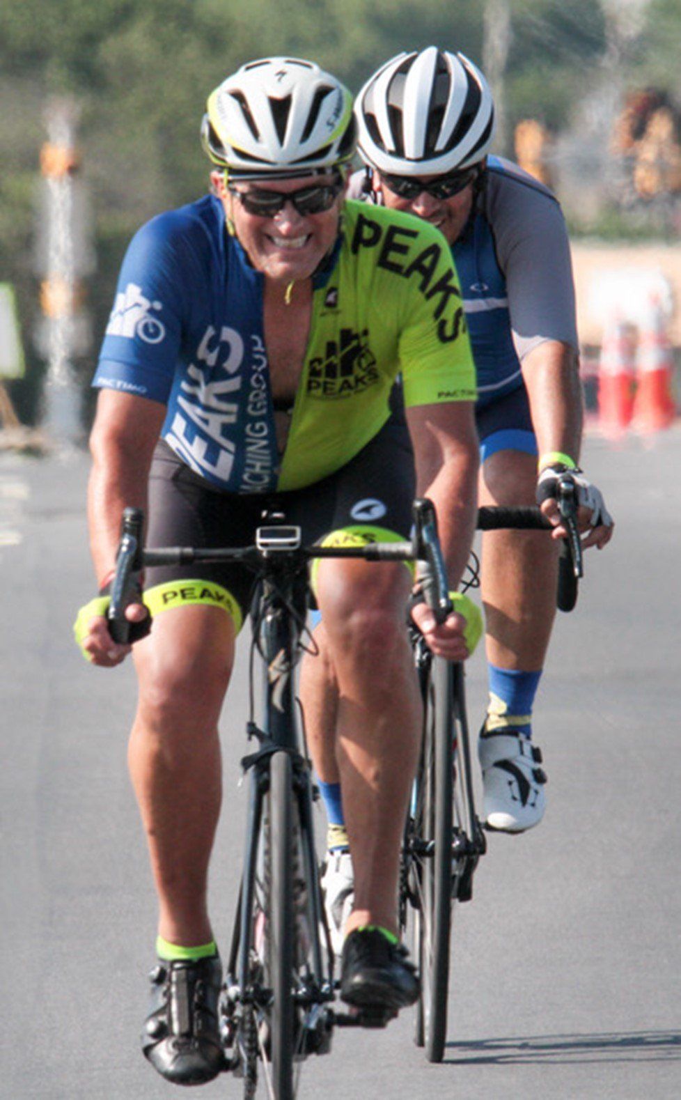 A man wearing a shirt that says peaks is riding a bike