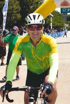 A man wearing a helmet and sunglasses is riding a bike
