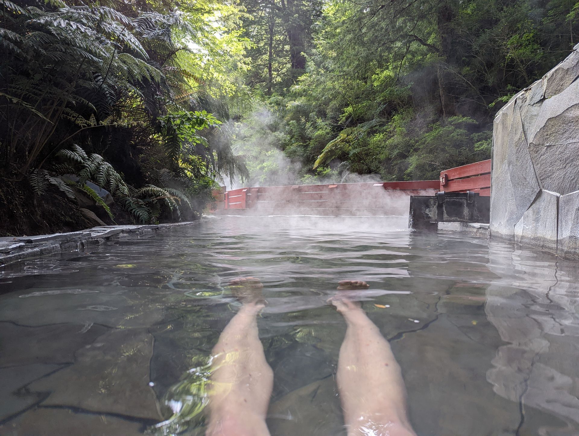 A person is laying in a hot tub with their feet in the water.