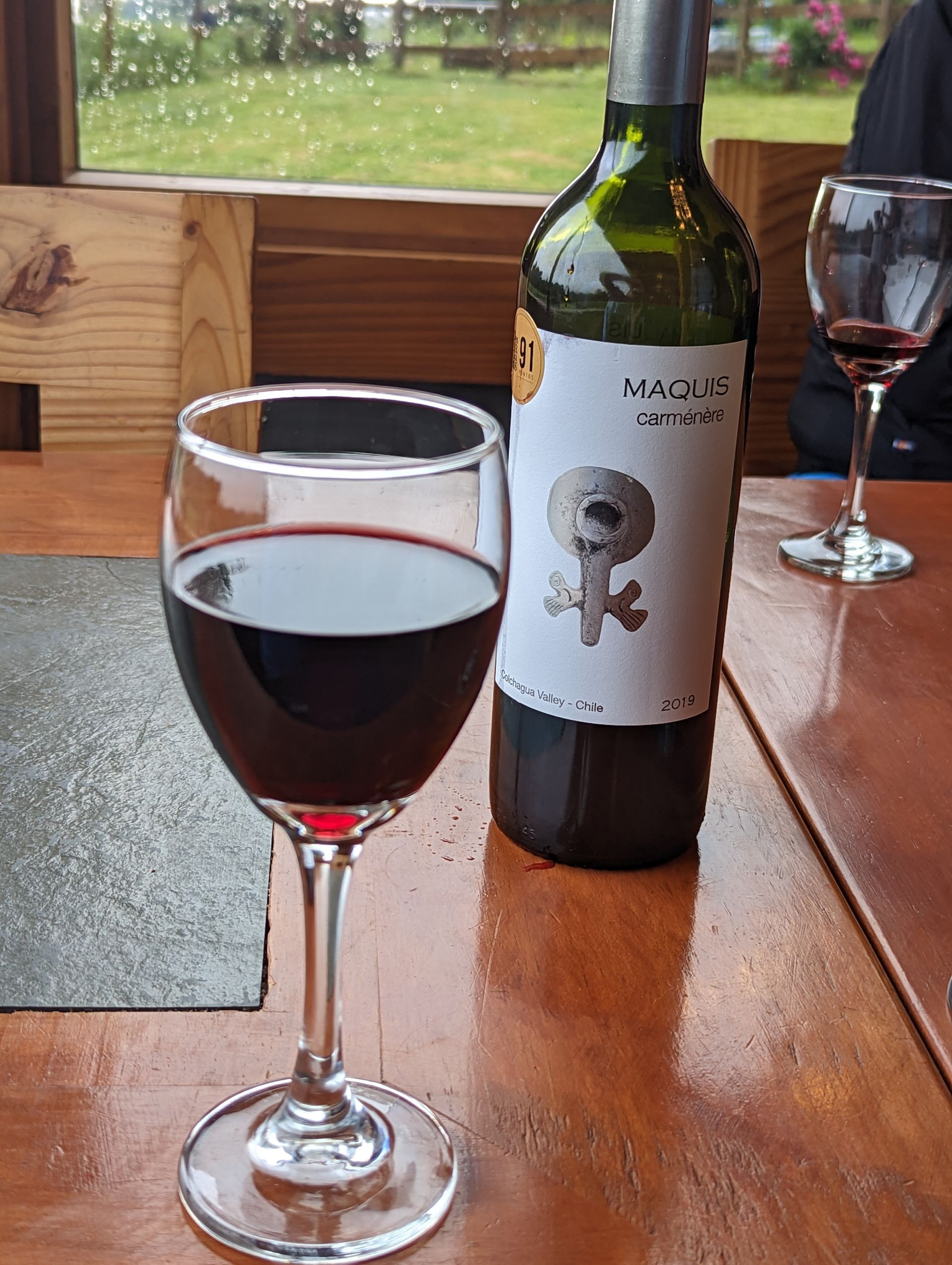 A bottle of wine and a glass of wine are on a table.
