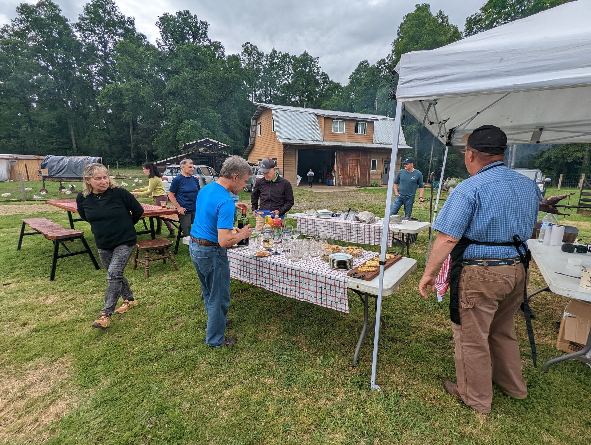 A group of people are standing around a table in a field.