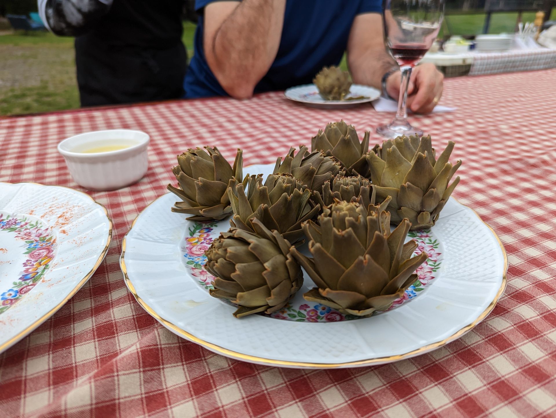 A plate of artichokes is on a checkered table cloth.