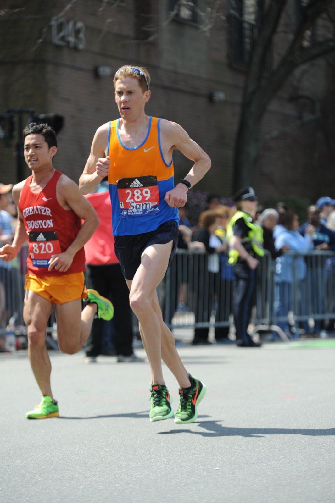 Two men are running in a marathon and one has the number 289 on his shirt