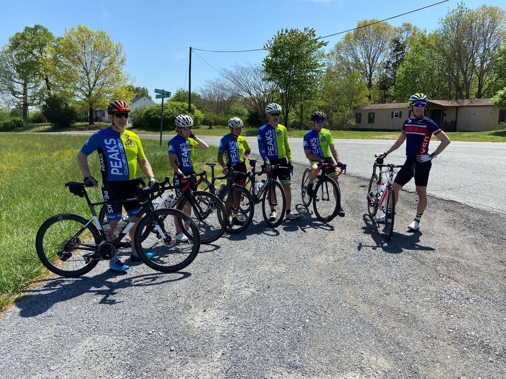 A group of cyclists are standing next to each other on the side of the road.