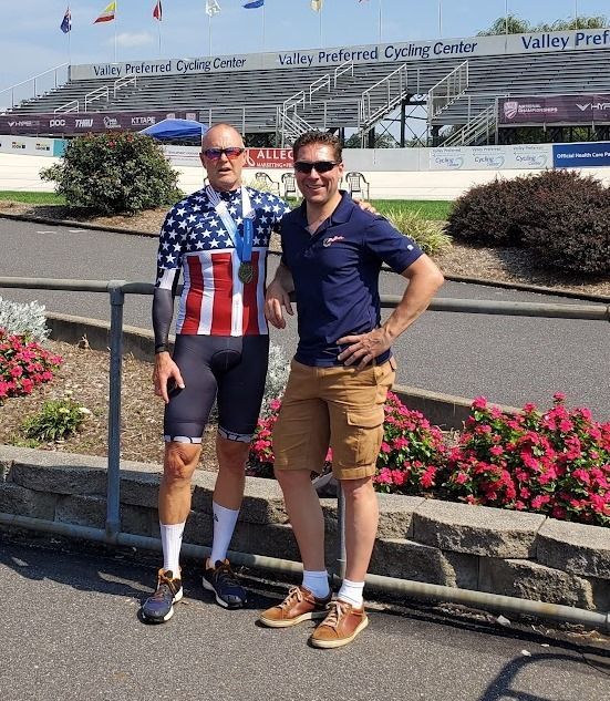 Two men standing next to each other with one wearing an american flag shirt