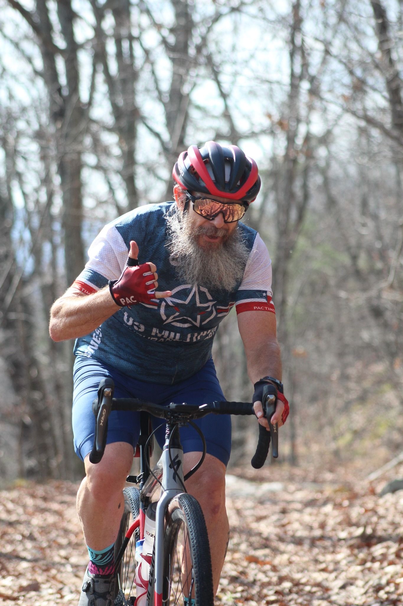 A man with a beard is riding a bike on a trail in the woods.