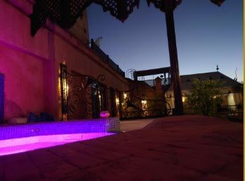 A swimming pool is lit up with purple lights at night