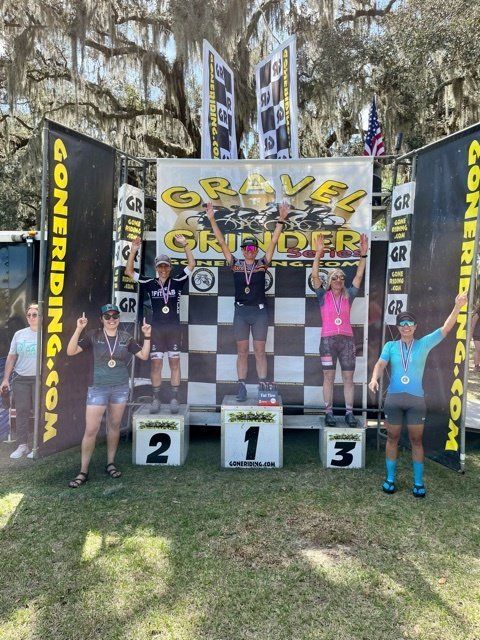 A group of people standing in front of a sign that says gravel grinder