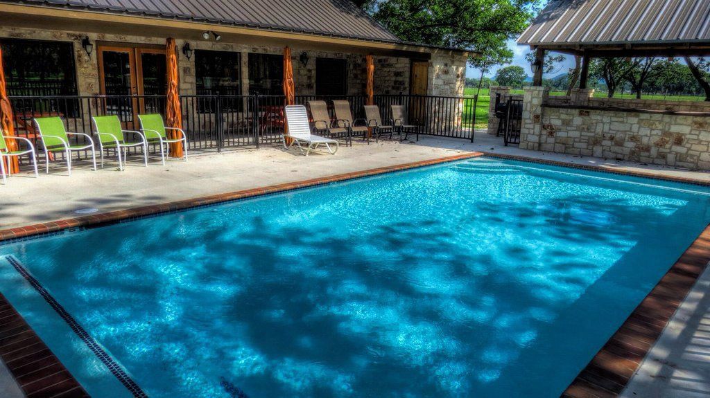 A large swimming pool surrounded by chairs and a building.