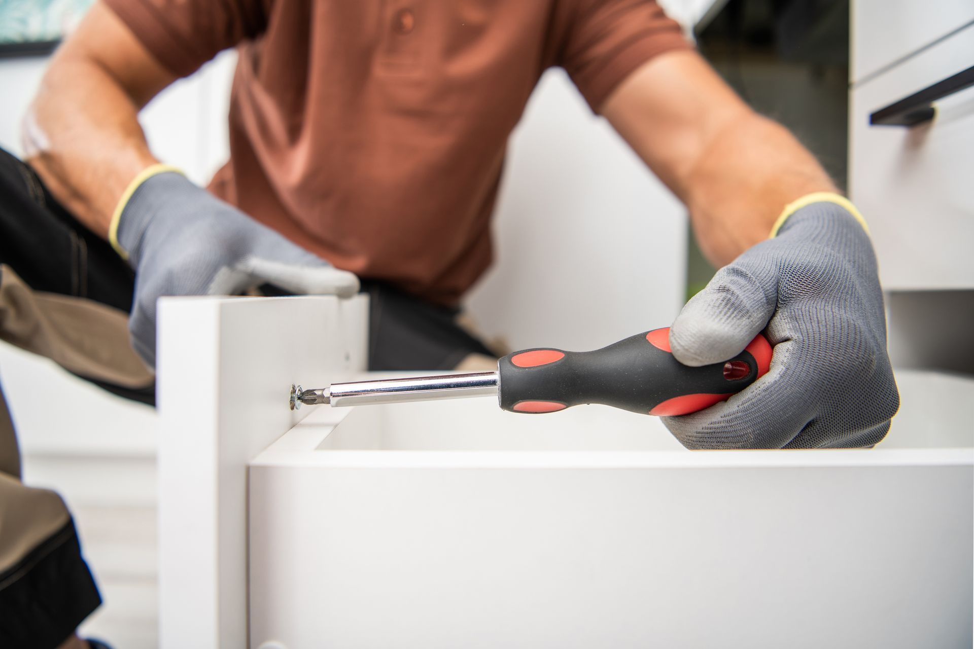 A man is fixing a drawer with a screwdriver.