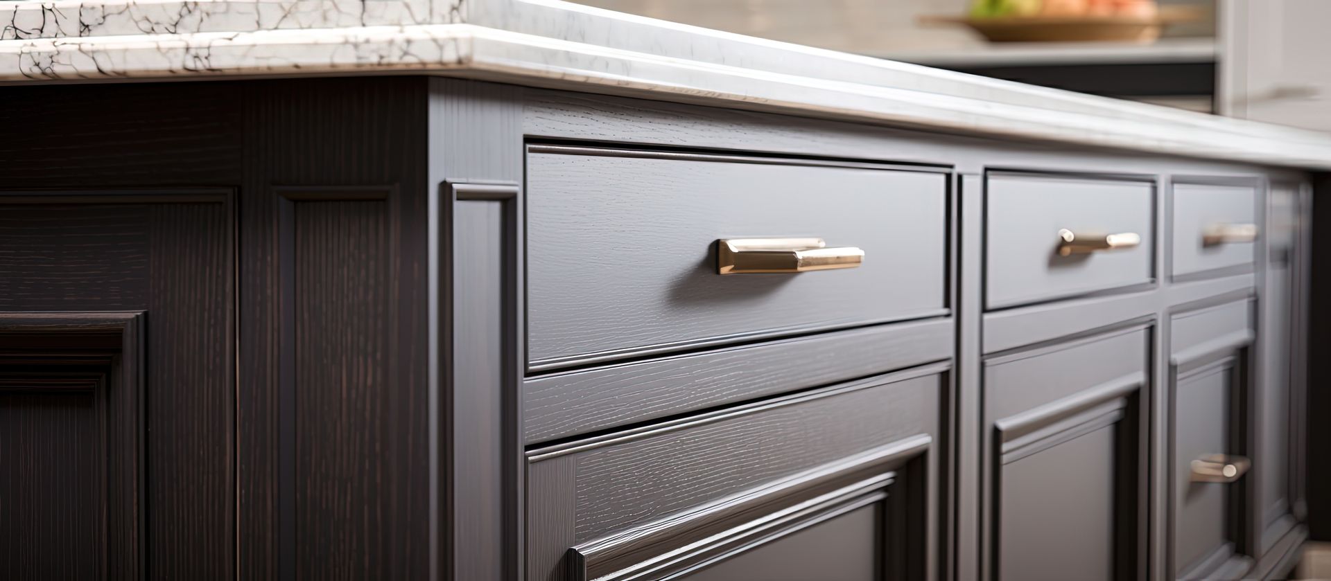 A kitchen with gray cabinets and a marble counter top.