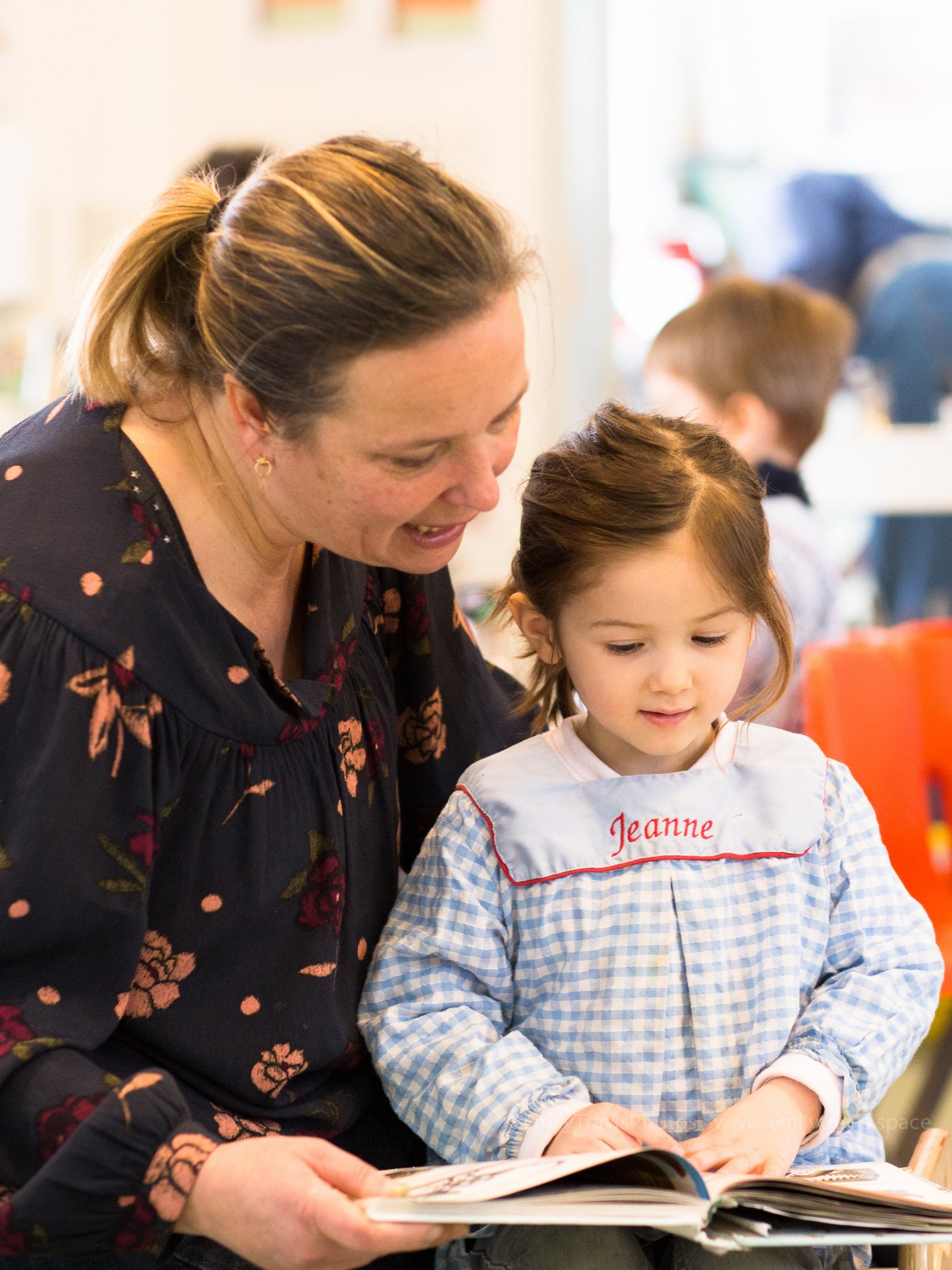 Woman reading a book with a child in a bright classroom