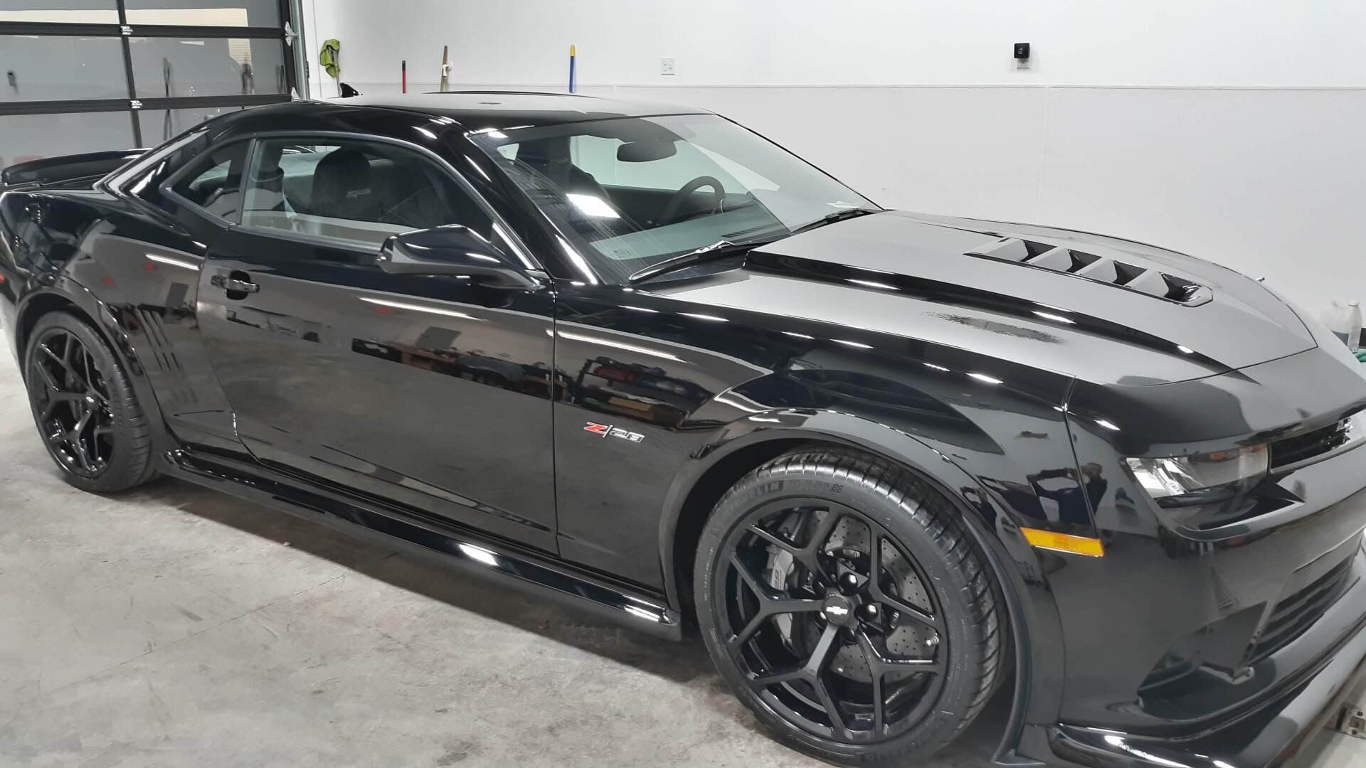 A black sports car is parked in a garage.