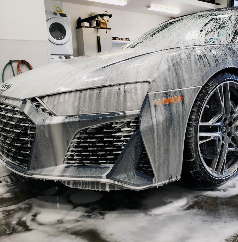 A car is covered in foam in a garage