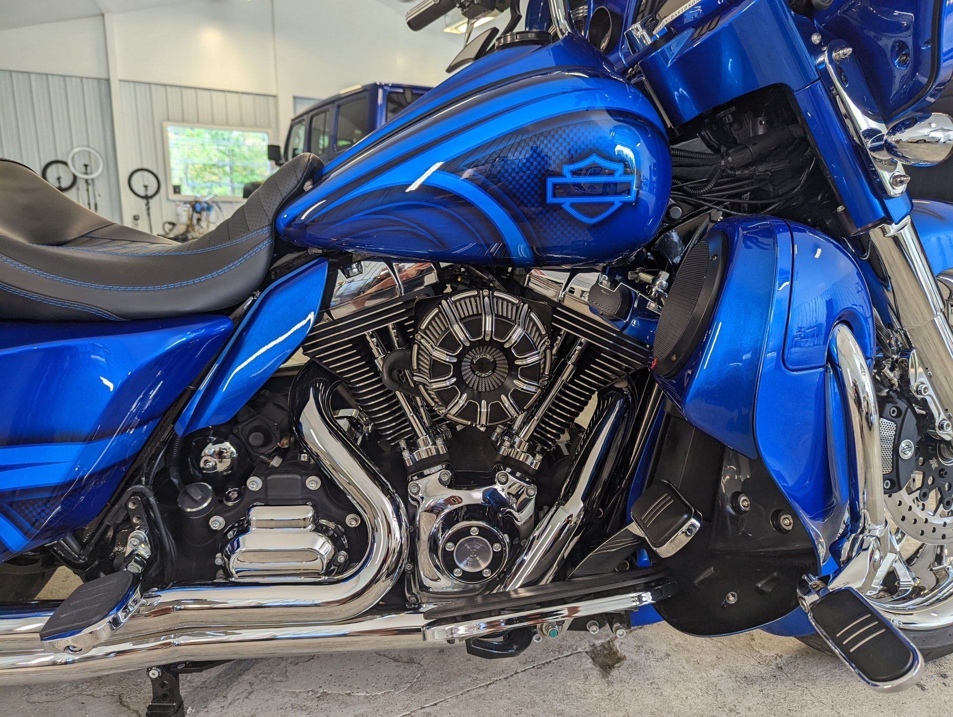 A blue harley davidson motorcycle is parked in a garage.
