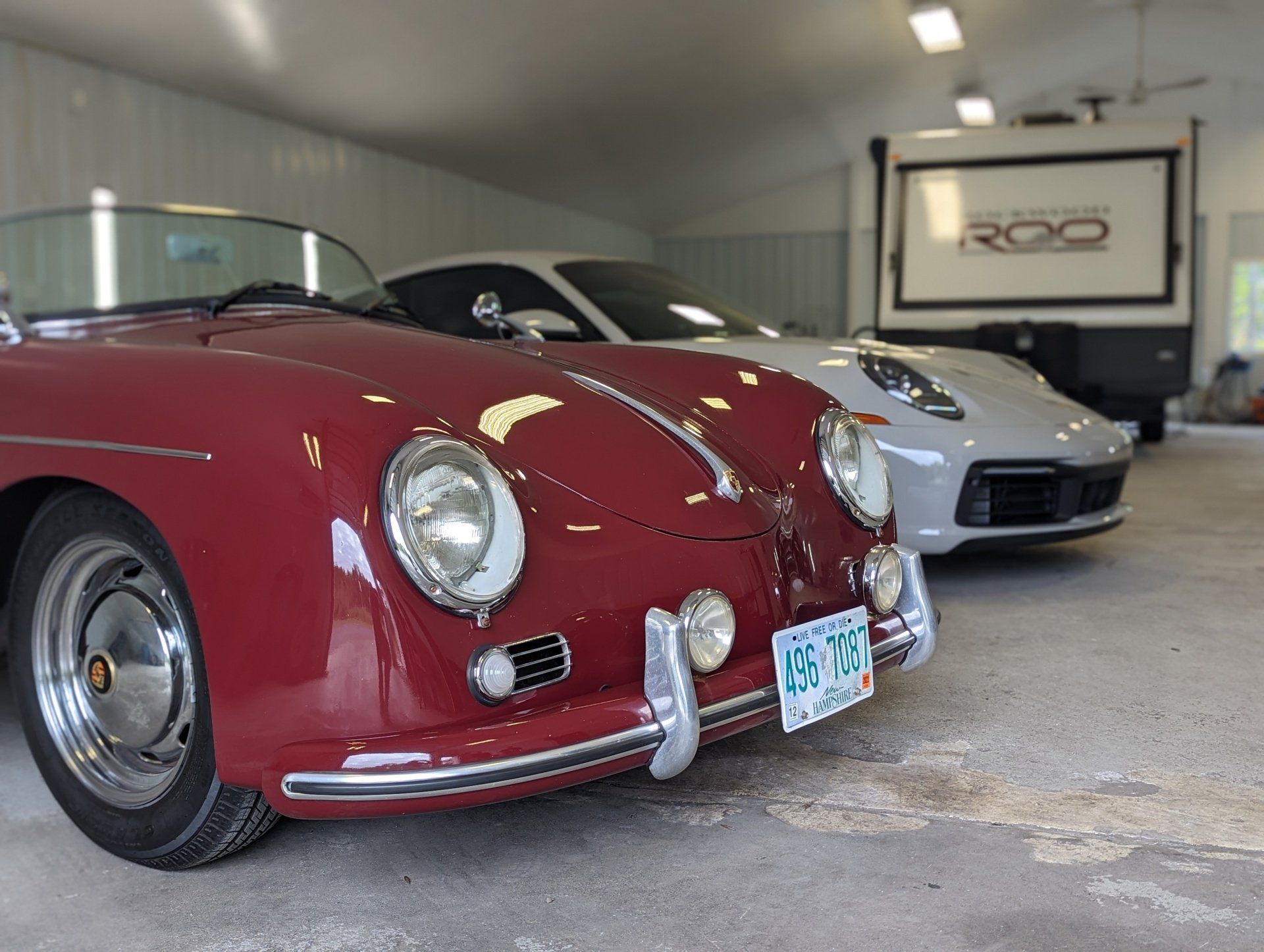 A red porsche is parked in a garage next to a white porsche