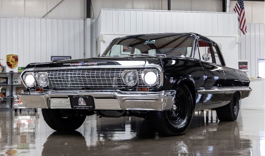 A black chevrolet impala is parked in a garage.