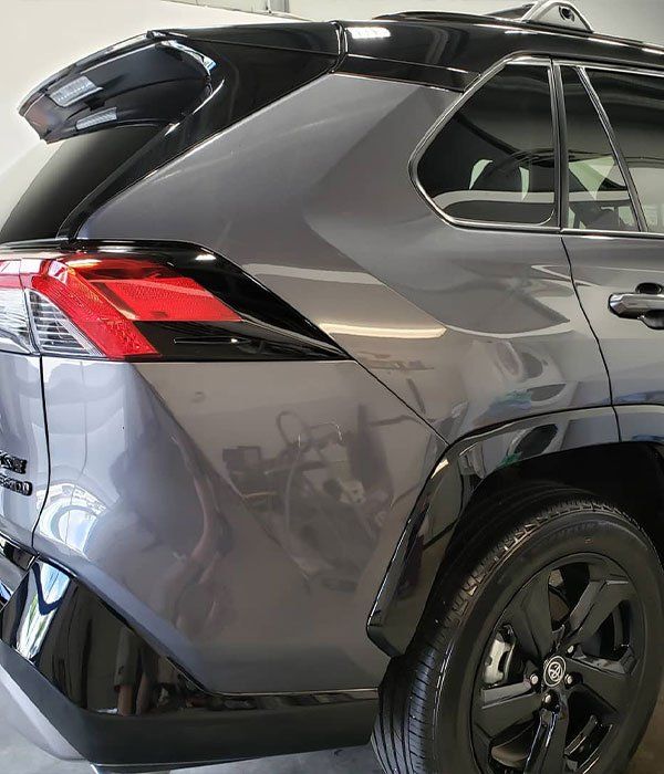 A gray suv with black wheels is parked in a garage.