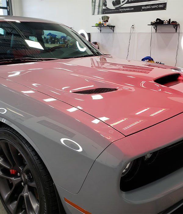 A red car is parked in a garage with the hood open