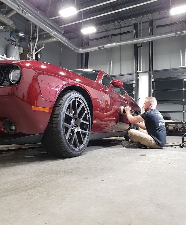 A man is working on a red car in a garage.