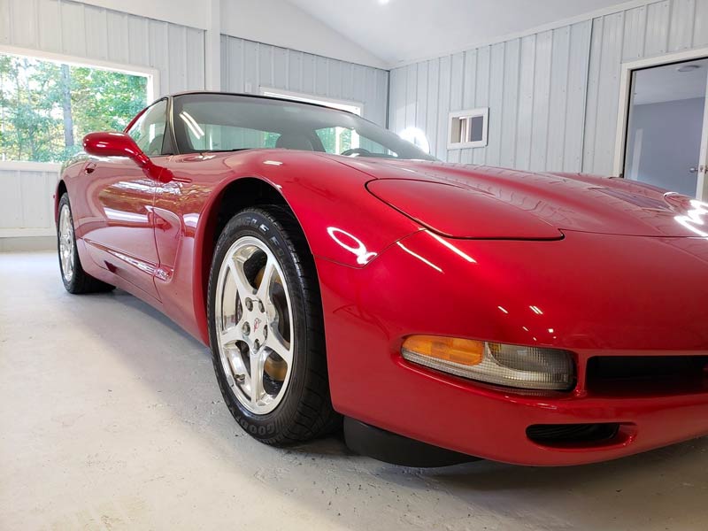 A red sports car is parked in a garage.