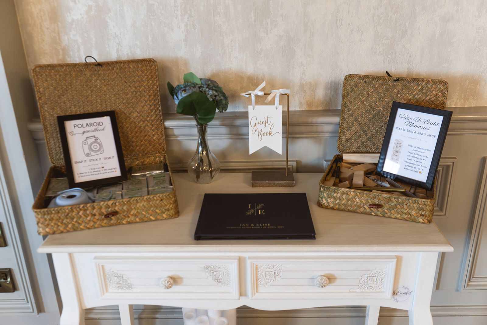 Decorated buffet table with open gift boxes, framed signs, flowers, and a black guest book on top