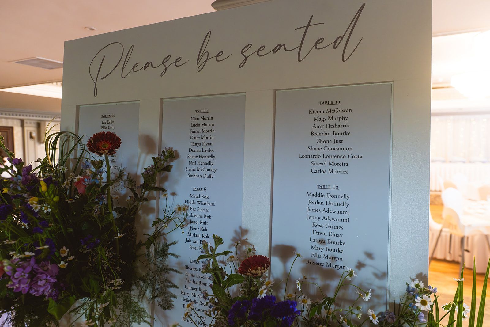 Seated chart at wedding with floral arrangements and calligraphy signage