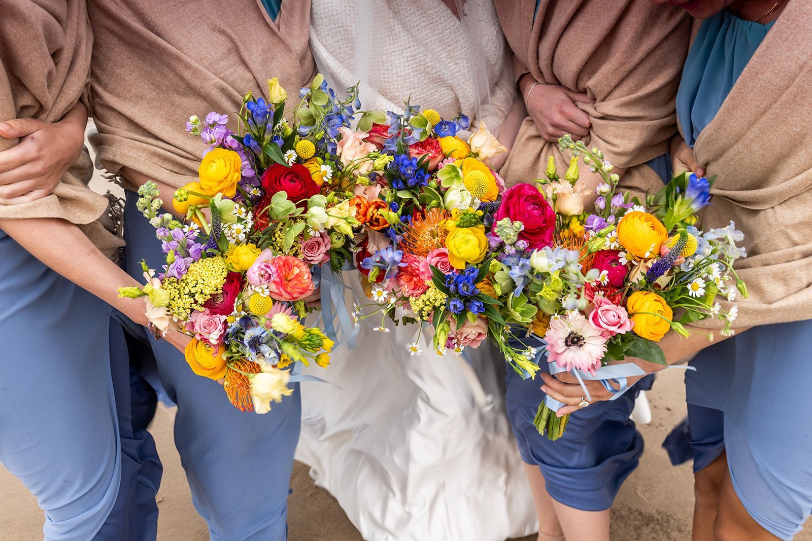 Two people holding colorful mixed flower bouquets in their laps, seated side by side.