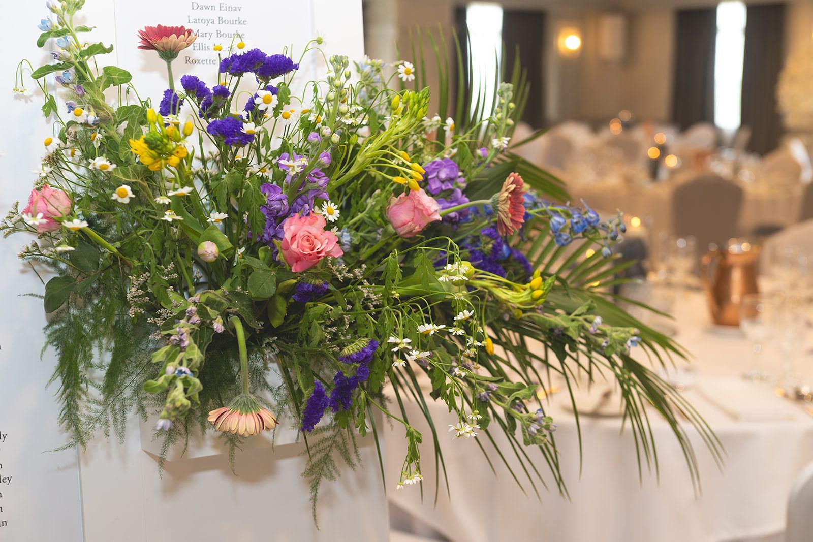 Large colorful floral centerpiece on a banquet table in a softly lit event hall