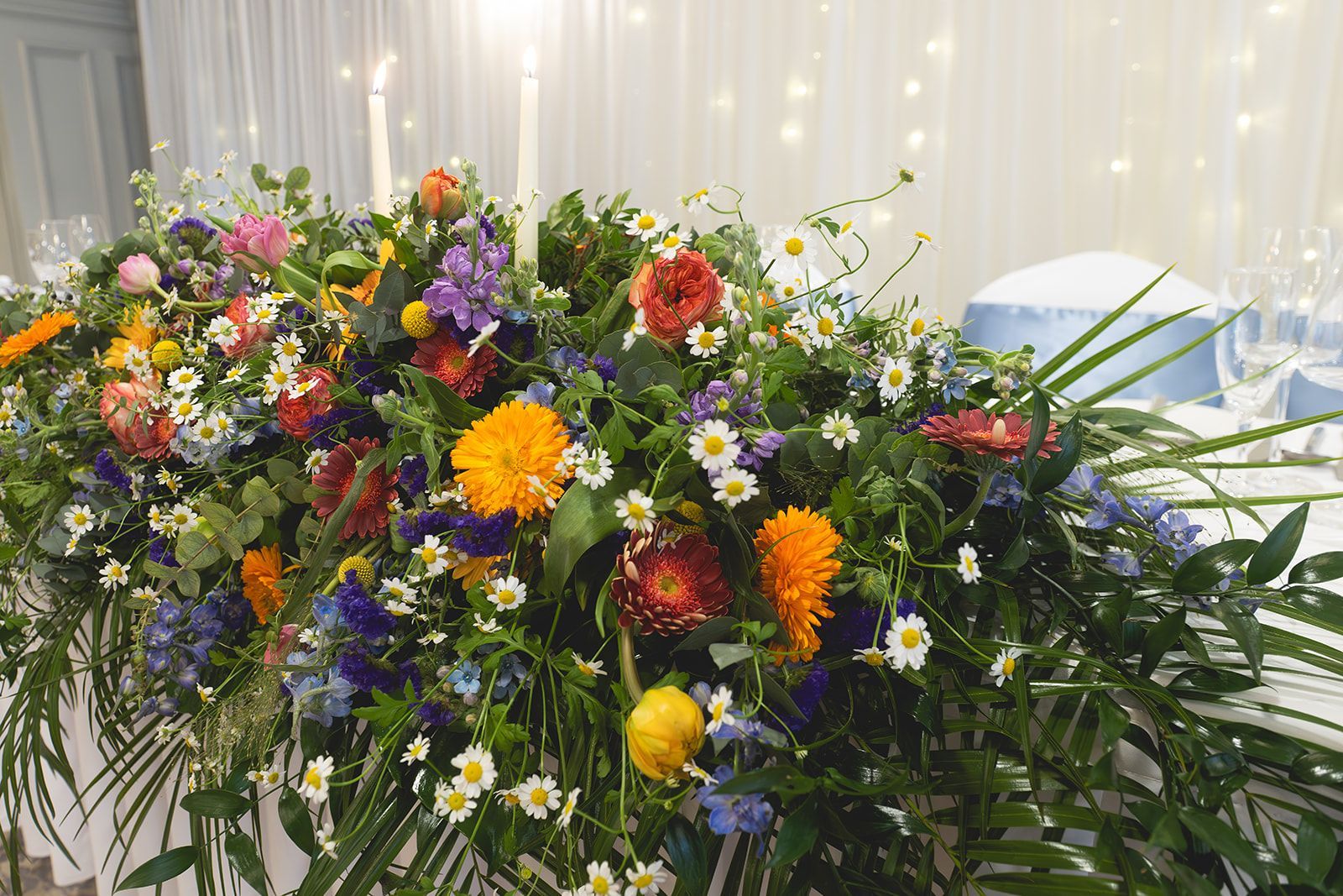 Colorful floral arrangement with orange, yellow, purple, and pink flowers on a decorated table